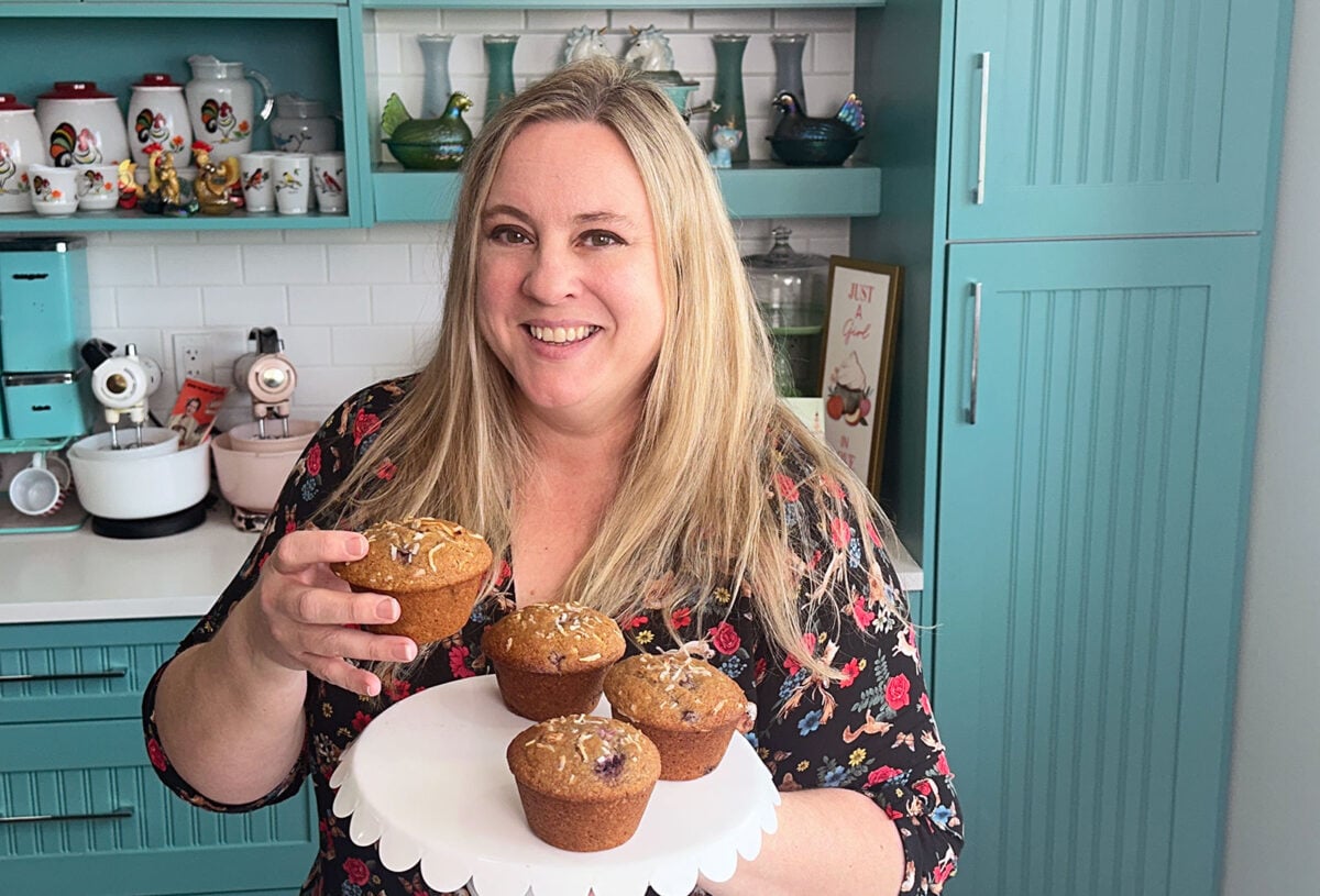 cherry coconut whole wheat muffins on a white platter with karlynn holding one up. 