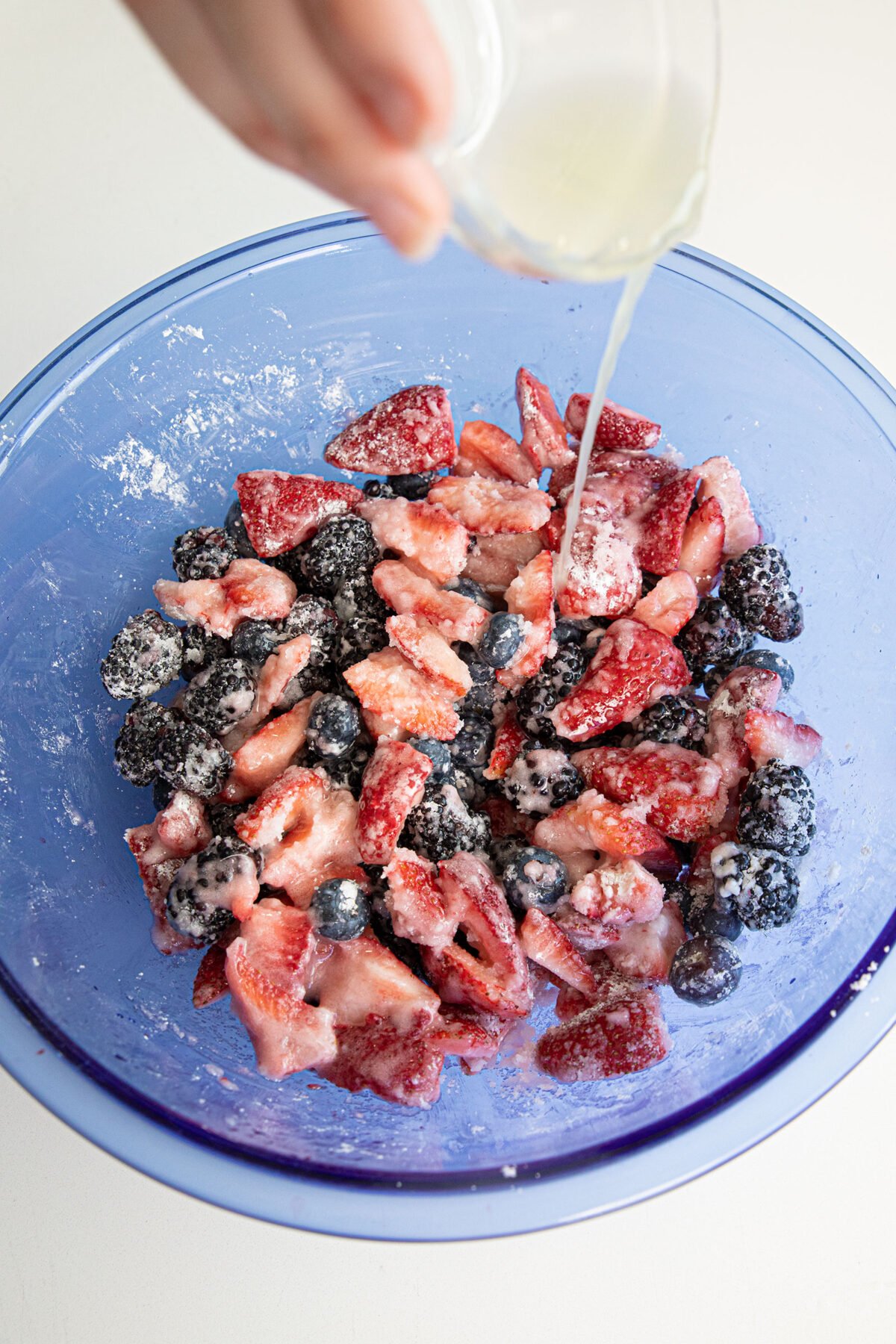 adding lemon juice to berries in a bowl