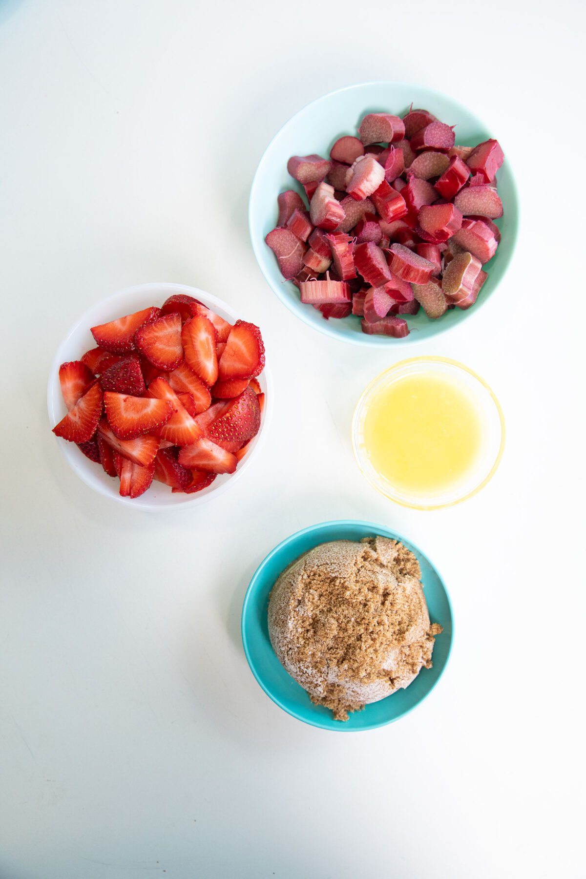 rhubarb and strawberries chopped up in bowls and other ingredients