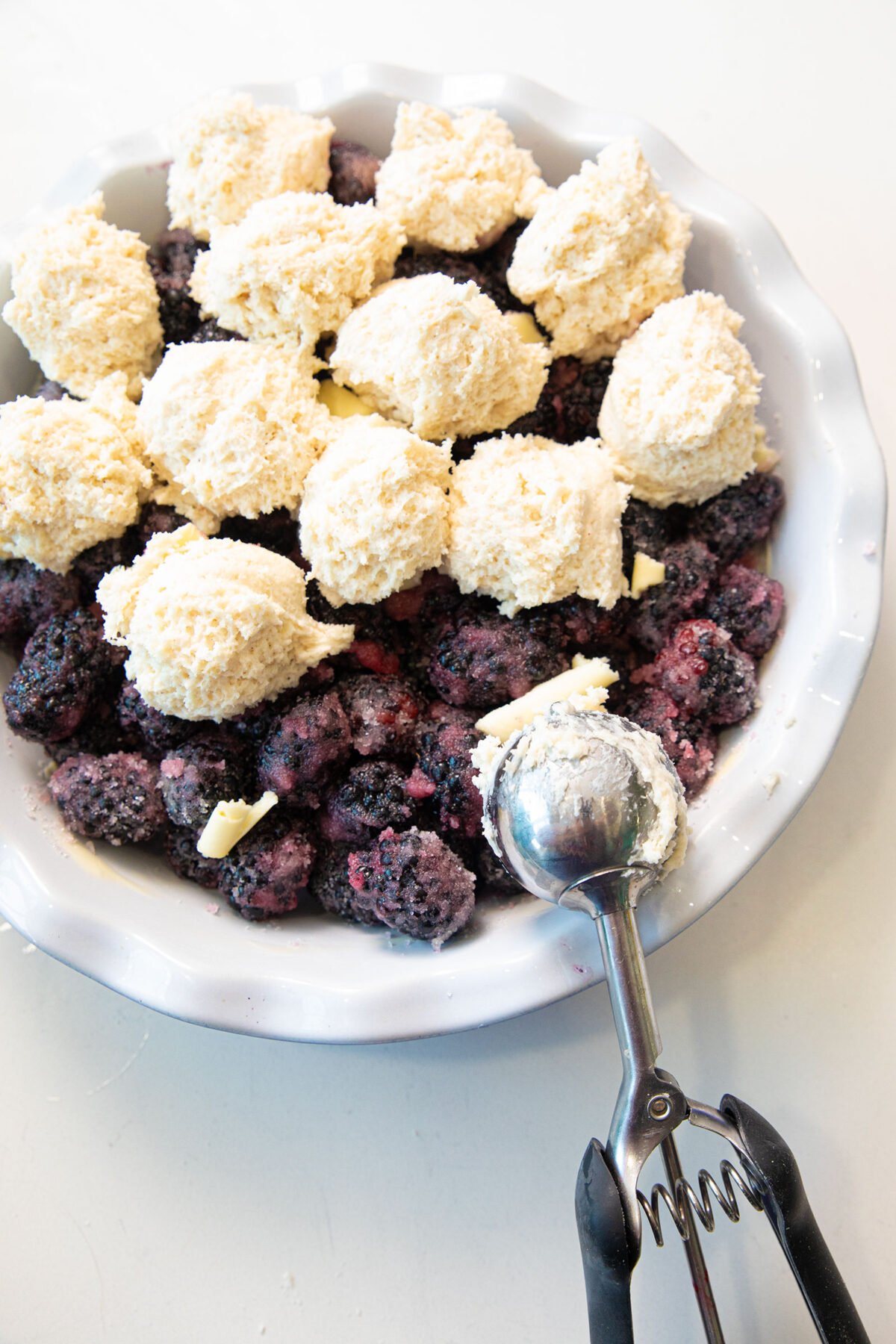 scooping the topping onto the blackberries in pie plate