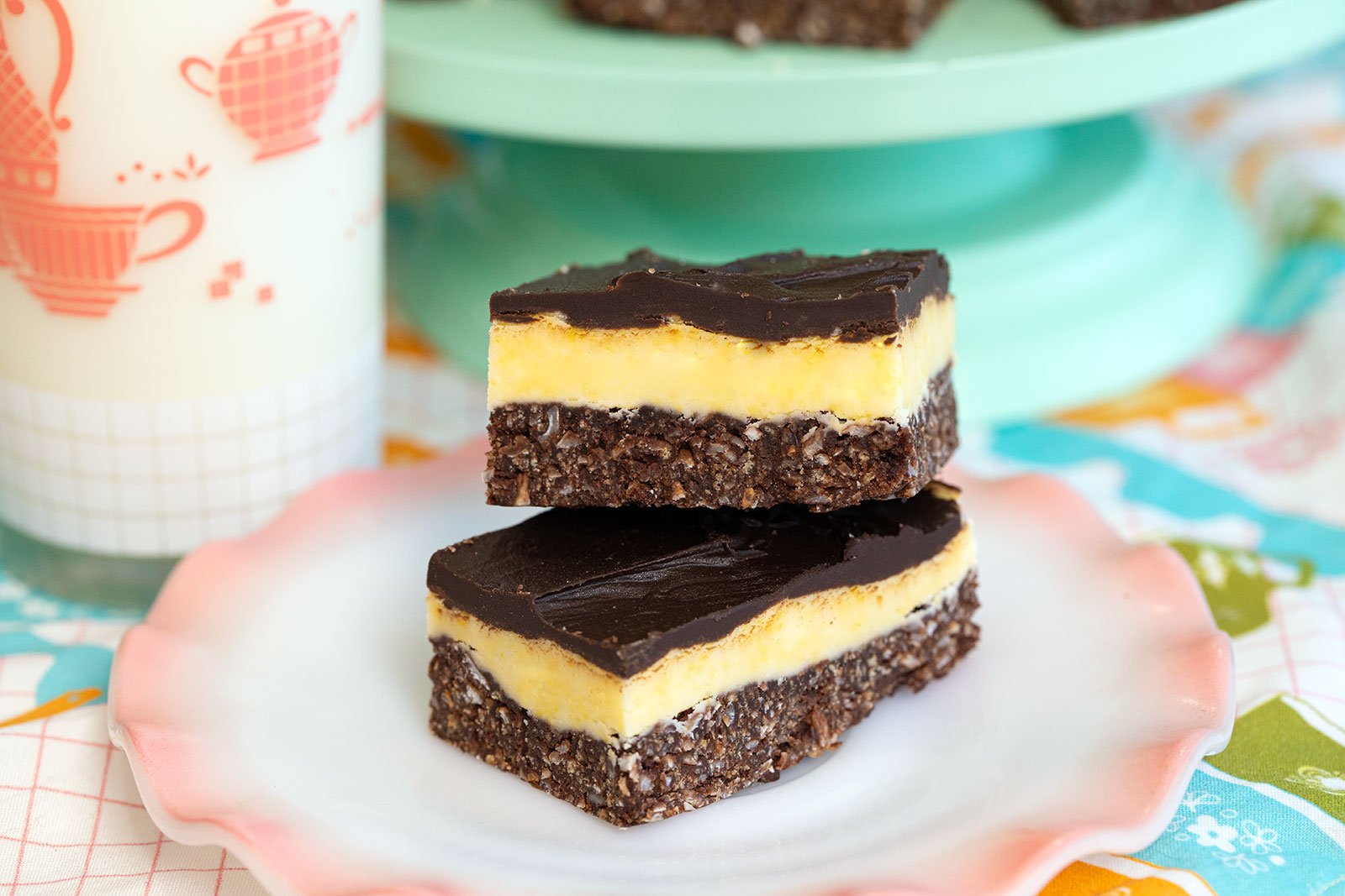 Classic Nanaimo bars on a pink plate with creamy chocolate layers.