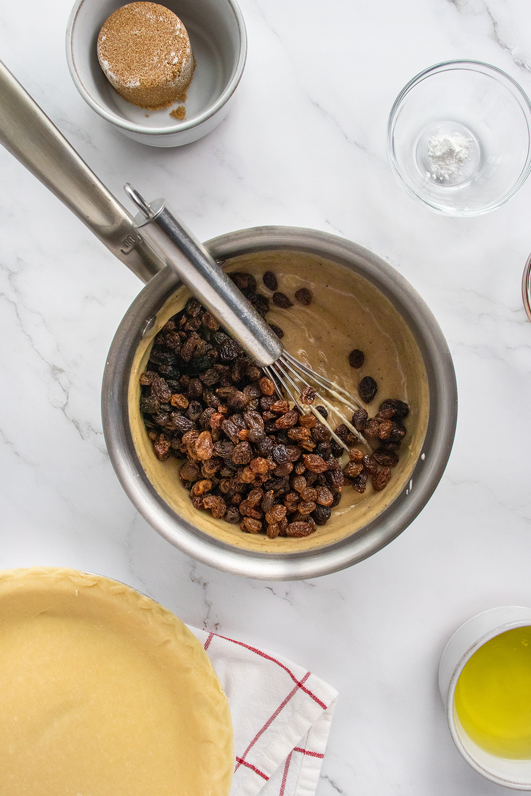A bowl of raisins and a whisk.