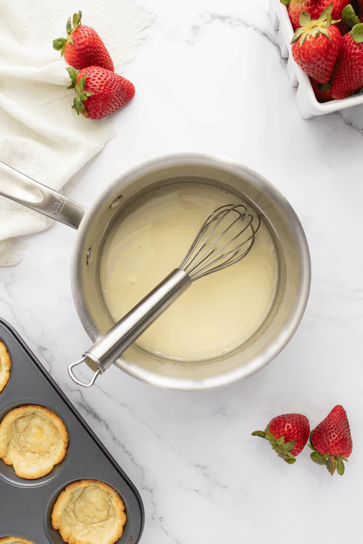 A pan with liquid in it and a whisk on top of it.