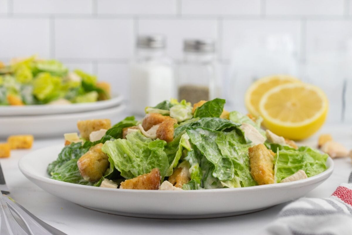 A plate of salad with croutons and a lemon.