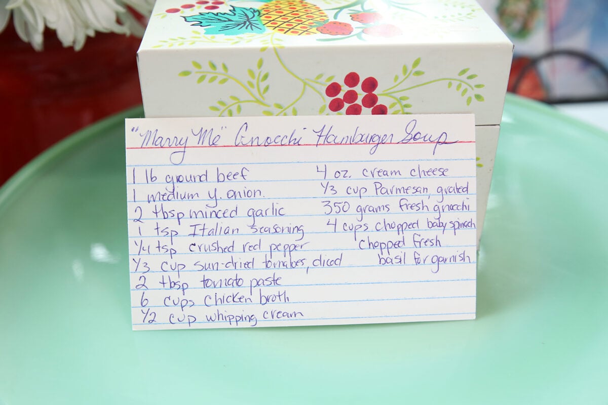 A handwritten recipe card for Marry Me Gnocchi Hamburger Soup is propped up in front of a decorative box, listing ingredients like ground beef, onion, garlic, tomato paste, broth, spinach, cream, and cheese.