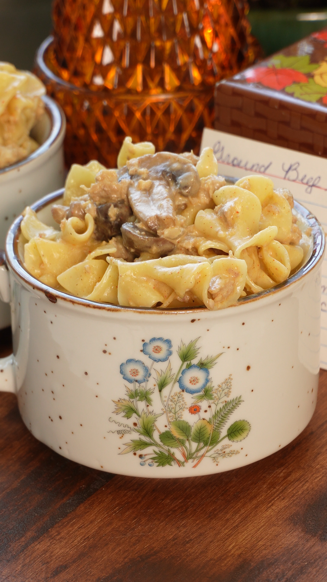 A ceramic bowl decorated with blue flowers filled with creamy beef and mushroom egg noodle stroganoff.