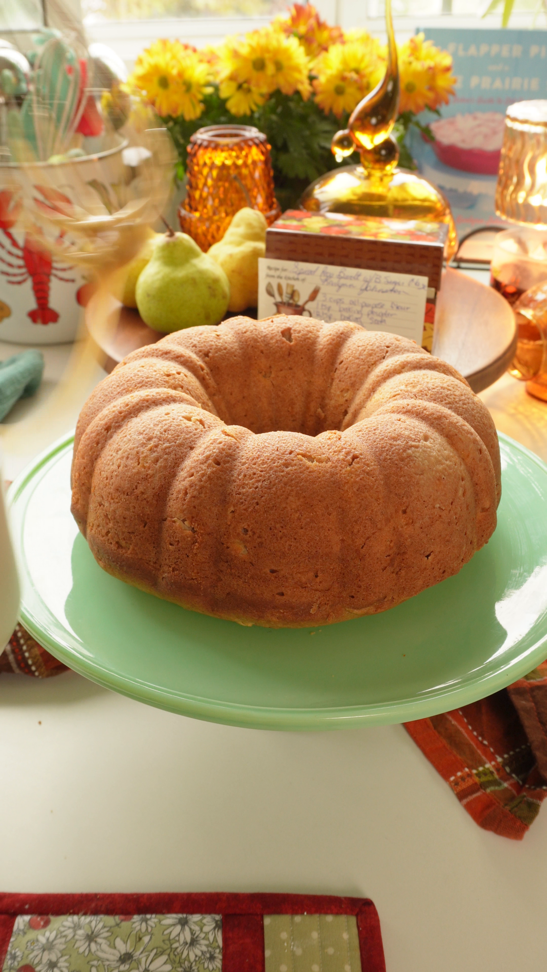 A round golden brown bundt cake on a light green cake stand.