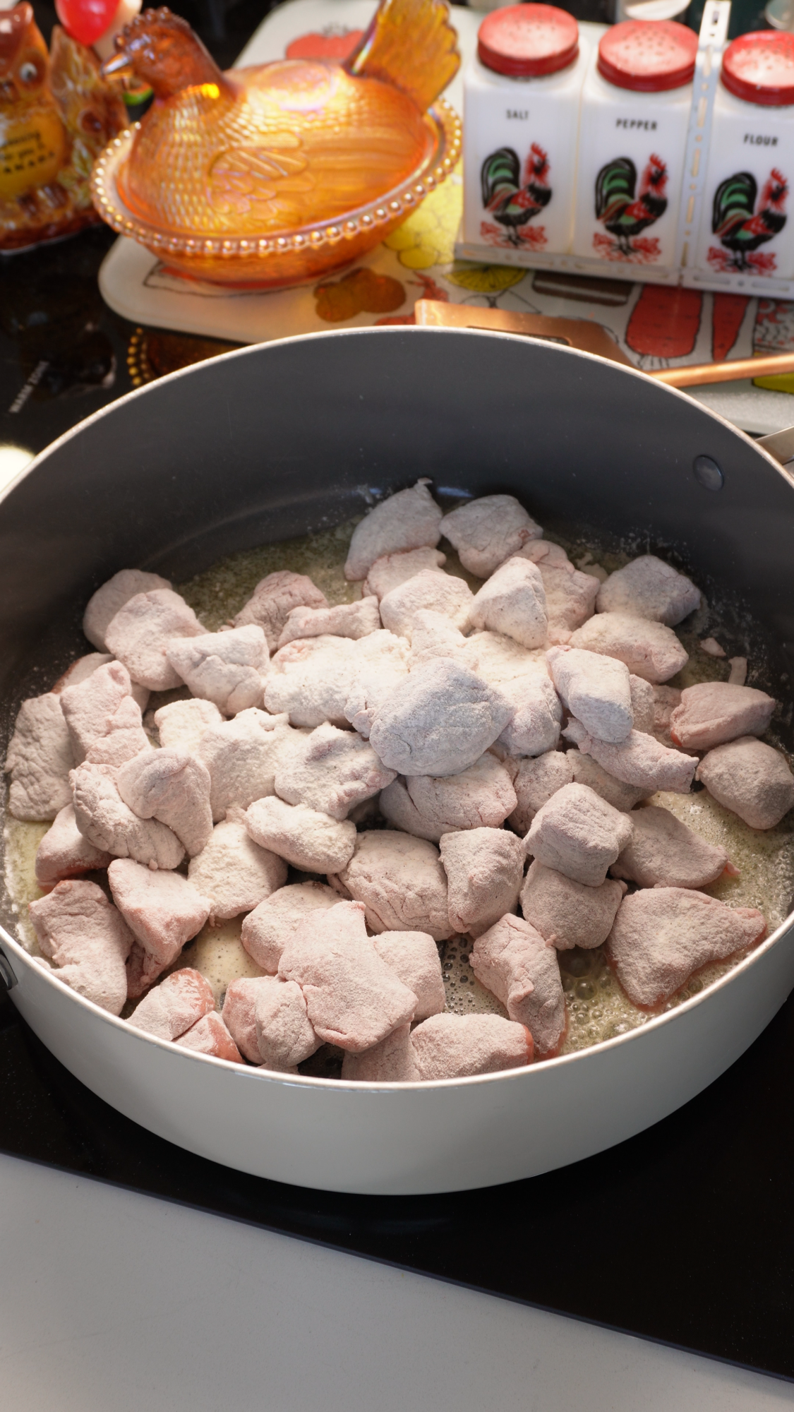 Flour-coated cubes of raw meat browning in a pan with melted butter.