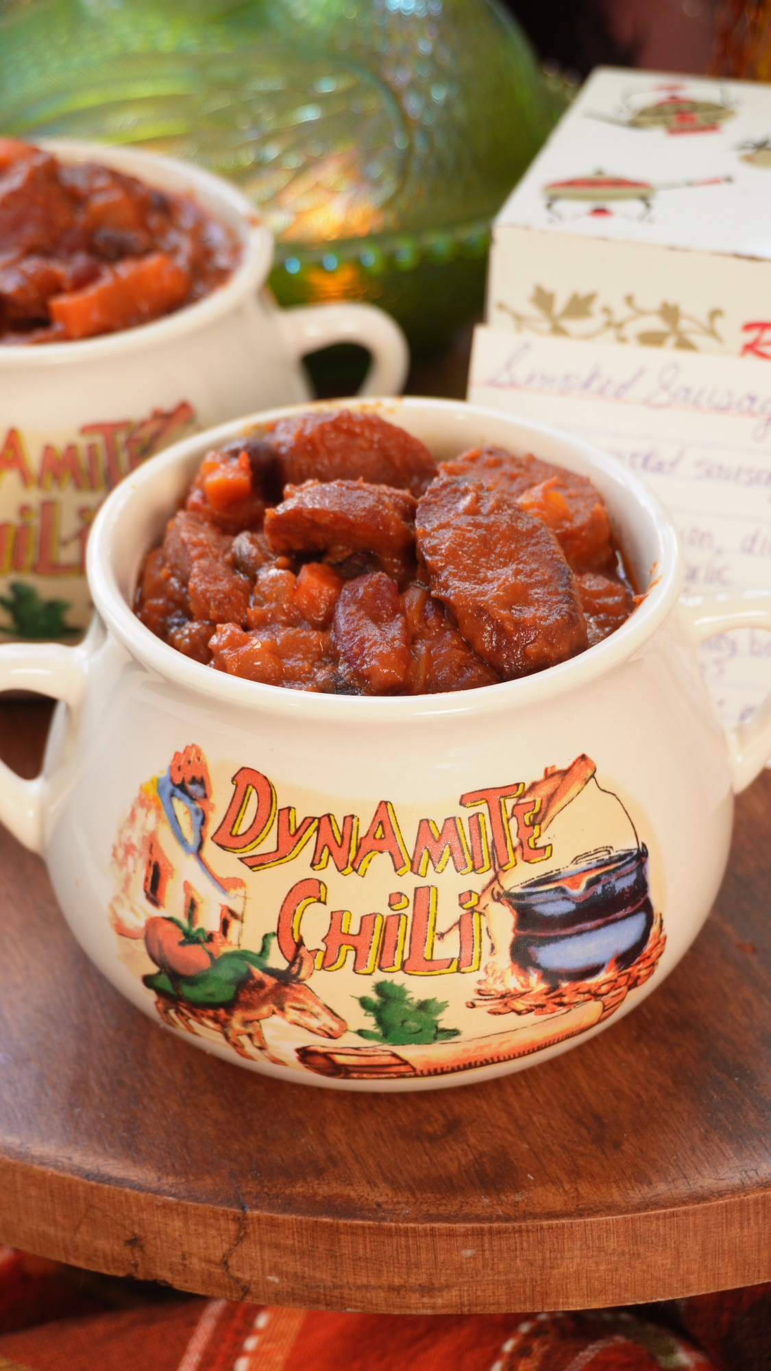Two white ceramic bowls filled with chili, featuring the text Dynamite Chili and a cartoon illustration of a cooking pot.
